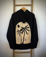 Hoodie negro oversize con capucha y estampado de palmeras y sol en la espalda.