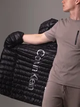 Campera acolchada Calvin Klein color negro, con capucha, cierre frontal con cremallera y bolsillos laterales con cremallera.