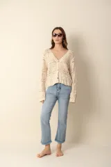 Cardigan color crema tejido al crochet con diseño calado, escote en V y cierre frontal con botones.