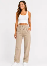 Pantalón de felpa color beige, de corte recto y holgado, con cintura elástica y cordón ajustable. Cuenta con bolsillos laterales.