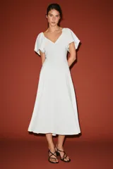 Vestido midi de color blanco, con escote en V y mangas cortas abullonadas.