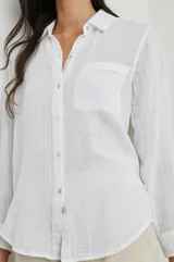 Camisa blanca de algodón con textura arrugada, corte clásico, cuello camisero, manga larga con puños abotonados y bolsillo de parche en el pecho.