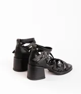 Sandalias negras de cuero con tiras cruzadas y hebillas plateadas.