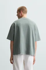 Camiseta gris de corte cuadrado y holgado, con cuello redondo y mangas cortas.