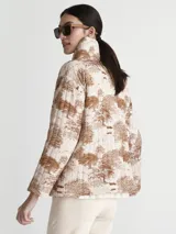 Saco acolchado con estampado toile de jouy en tonos beige y marrón, con cuello alto y cierre frontal con botones negros.