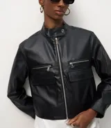 Campera de cuero sintético (PU) color negro, con cuello alto, cierre frontal con cremallera, dos bolsillos superiores con cremallera y dos bolsillos inferiores con solapa.