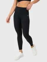 Calza deportiva de tiro alto con tecnología seamless y largo ankle. Presenta un diseño liso en color negro con logo pequeño en la cadera.