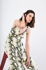 Vestido midi con estampado de piel de serpiente en tonos beige, negro y amarillo. Tiene breteles finos cruzados en la espalda y corte recto.