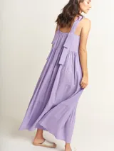 Vestido largo lila con volados en diferentes tamaños, escote cuadrado y lazos en la espalda.