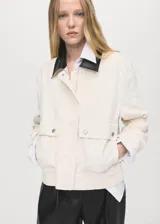 Chaqueta recta de algodón estilo vaquero, color blanco, con manga larga, cuello camisero de efecto piel en contraste, cierre oculto de cremallera y botones, y dos bolsillos delanteros de parche con solapa.