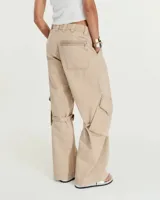 Pantalón cargo de tiro medio confeccionado en gabardina de algodón y lino con efecto gastado. Presenta una silueta de pierna recta y ancha, con bolsillos laterales inclinados y bolsillos cargo con tapa en las rodillas. Incluye tiras ajustables con hebillas metálicas en los laterales para modificar la silueta, cierre metálico y bolsillos traseros.