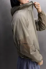 Chaqueta cortavientos de tejido técnico con estructura ripstop, cuello subido con capucha, cierre frontal de cremallera, bolsillos laterales ocultos y zonas perforadas para mayor transpirabilidad.