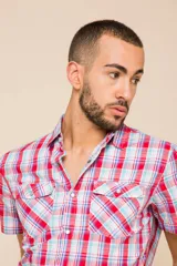 Camisa de manga corta con estampado de cuadros en tonos verdes, azules y blancos. Presenta cuello clásico, cierre frontal con botones y dos bolsillos delanteros con solapa.