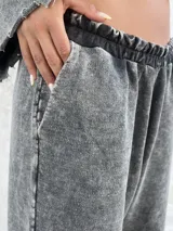 Pantalon de estilo deportivo con efecto lavado nevado, corte holgado y bolsillos laterales. Presenta costuras expuestas y cintura elástica.