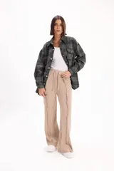 Pantalón de tejido de punto color beige, de corte recto y holgado, con cintura elástica con cordón ajustable y detalle de costuras desflecadas verticales en el frente.