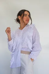 Camisa blanca de algodón estilo romántico con tejido broderie, mangas largas con puños volados y detalles de volados frontales.