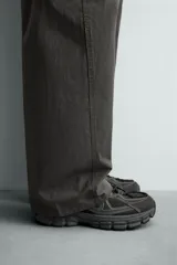 Zapatilla deportiva de estilo running, completamente negra, con capellada de malla y superposiciones sintéticas. Presenta una suela gruesa y voluminosa con diseño segmentado.