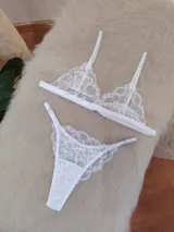 Conjunto de lencería compuesto por un bralette triangular de encaje con breteles regulables y una tanga colaless regulable con detalle de encaje.