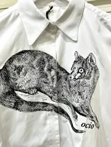 Camisa blanca de algodón con cuello clásico, manga larga con puños abotonados y estampado frontal de un animal similar a un zorro.