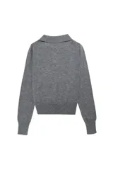 Suéter tejido de punto color gris, con cuello polo y escote en V con un botón. Tiene mangas largas y está confeccionado en un tejido suave y liviano.