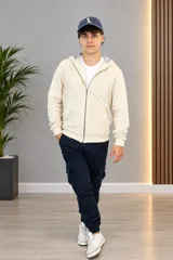 Campera con capucha de punto color beige, con cierre frontal y bolsillos tipo canguro.