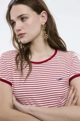 Remera baby blanca de algodón, de corte cropped al cuerpo y mangas cortas. Presenta ribetes negros en contraste en el cuello redondo y los puños, con un estampado localizado de un ají rojo con la inscripción 'Pimentón' en el centro del pecho.