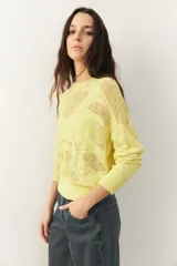 Sweater amarillo calado de manga larga con cuello redondo, puños y cintura elastizados.
