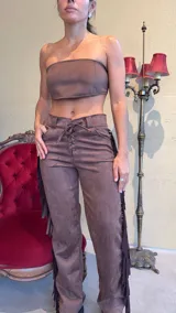 Pantalón marrón de gamuza con flecos laterales y ajuste con cordones en la cintura.
