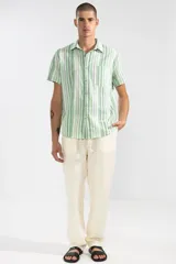 Pantalón de lino color crema, de corte recto y fit relajado. Tiene cintura elástica con cordón de algodón, bolsillos laterales y traseros.