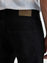Pantalón de jean negro, de corte recto, con bolsillos delanteros y traseros.