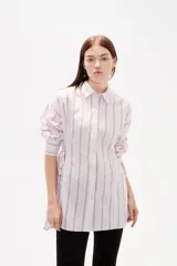 Camisa de viscosa con estampado de rayas verticales, cuello camisero, cierre frontal con botones y detalle de ajuste lateral con cordones.