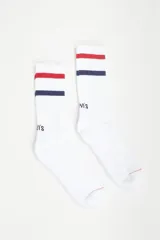 Pack de dos pares de medias blancas de caña media, con detalle de franjas horizontales en rojo y azul marino en la parte superior y logo de la marca bordado.