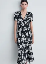 Vestido midi de corte evasé con estampado floral en blanco y negro. Presenta cuello de pico, mangas cortas y detalles de blonda en la cintura.