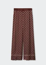 Pantalon palazzo de tejido satinado color bordó con estampado de lunares blancos. Presenta tiro medio, cintura elástica, bolsillos laterales y detalle de ribete en el ruedo.