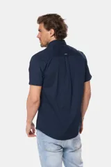 Camisa lisa de manga corta color crema, confeccionada en 100% algodón, con cuello abotonado y un bolsillo en el pecho.