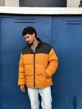 Campera puffer color mostaza con cuello alto y cierre frontal con cremallera.