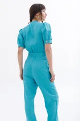 Mono negro de lino con escote pronunciado en V y nudo frontal que deja ver un corte en la cintura. Mangas cortas abullonadas y pantalón de corte recto.