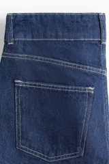 Short de denim azul de tiro alto, confeccionado en algodón rígido con diseño de cinco bolsillos, corte holgado, cierre y doble botón metálico en la cintura.