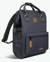 Mochila de diseño urbano en color azul marino, con detalles en cuero sintético marrón y negro. Cuenta con compartimento principal con cierre, bolsillo frontal con cierre, asas superiores reforzadas y base reforzada.