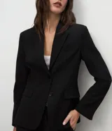 Blazer de corte sastre color negro, con cuello de solapas, cierre frontal de dos botones y forro interno. Presenta una estructura recta y refinada.