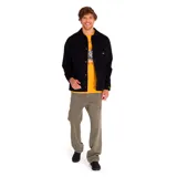 Chaqueta tipo coach de color negro, confeccionada en tejido twill de algodón. Presenta cierre frontal con botones a presión, cuello clásico, puños elásticos y múltiples bolsillos frontales, incluyendo bolsillos en el pecho y en la parte inferior. Incluye etiqueta con logo de la marca en el pecho.