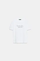 Camiseta de algodón de corte regular con cuello redondo y manga corta. Presenta un estampado de texto a contraste en la parte frontal y bajo recto.