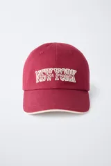 Gorra de béisbol azul marino con visera curva y detalle de borde en color crema. Presenta un bordado frontal con la palabra 'LONDON' en tipografía estilo varsity y texto adicional debajo.