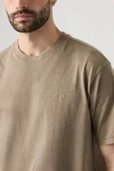 Remera de algodón con cuello redondo y mangas cortas, de corte relajado y color marrón con efecto desgastado. Presenta un pequeño logo bordado en el pecho.