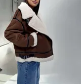 Campera tipo gamulán color chocolate con interior y solapas de corderito sintético en color blanco. Presenta detalles de costuras y bordes en cuero sintético negro, cierre frontal cruzado y cinturón ajustable en el ruedo.