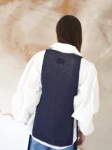 Chaleco de punto azul con escote en U pronunciado y laterales abiertos.