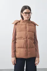 Chaleco puffer negro con diseño acolchado, capucha desmontable y cierre frontal. Cuenta con cordones ajustables en la cintura y bolsillos laterales.