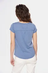 Remera color beige con cuello redondo, mangas cortas, bolsillo pequeño en el pecho y media botonadura frontal.