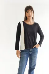 Remera de manga larga en color azul, con diseño asimétrico que presenta una franja lateral en color beige. Posee cuello redondo, corte más corto en la parte delantera y más largo en la trasera, con aberturas laterales y detalles de pespuntes visibles.