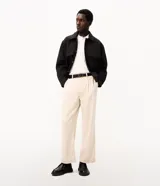 Pantalón de vestir beige de corte wide leg, con trabillas para cinto, bolsillos y diseño de sastrería.